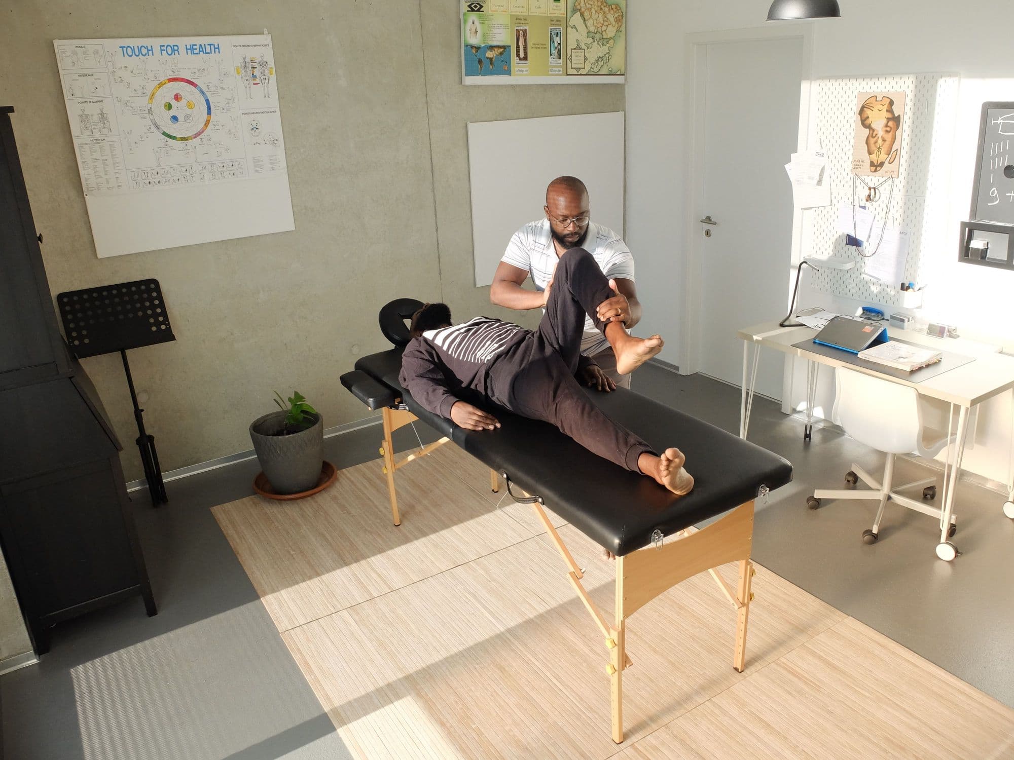 A therapist guiding a client's leg through a stretch on a treatment table