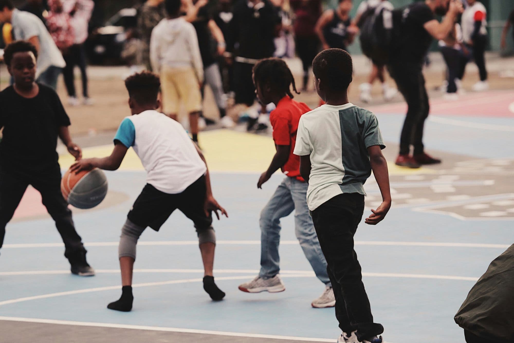 Children playing basketball together on an outdoor court